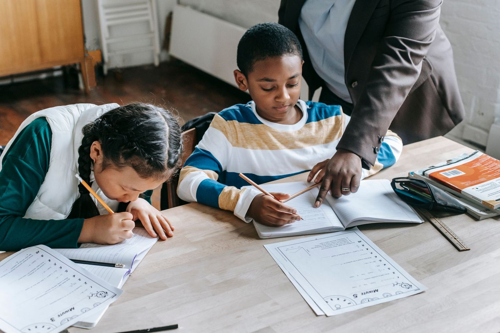 A teacher helping two young learners with their work
