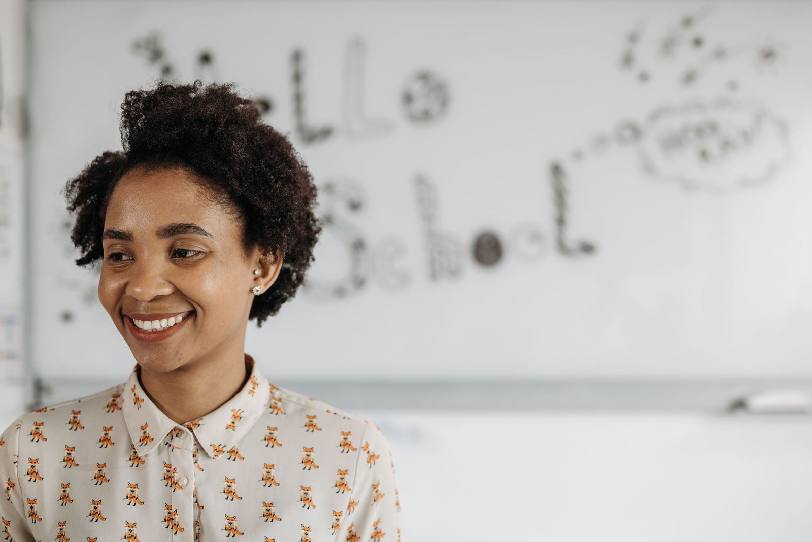 A smiling teacher in front of a whiteboard